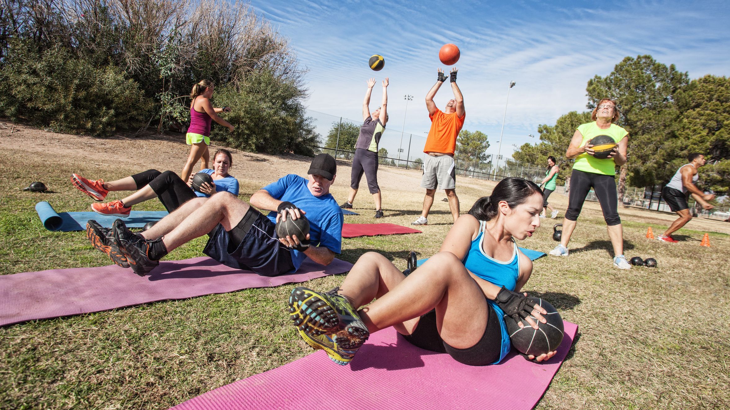 Auf dem Bild sind mehrere Personen zu sehen, die Outdoor verschiedene Functional Fitness-Übungen machen.